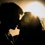 man and woman kissing under the sun