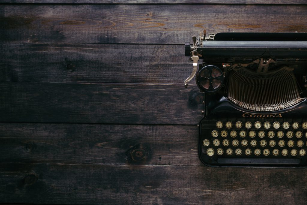 black corona typewriter on brown wooden planks