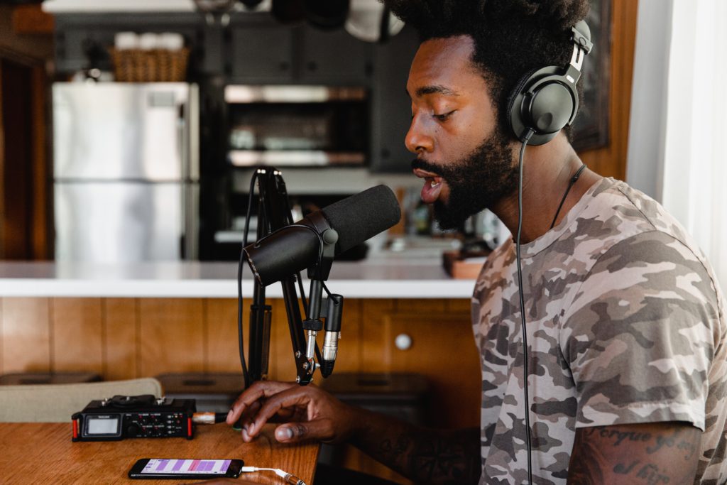 man in green and beige camouflage shirt sitting in front of microphone