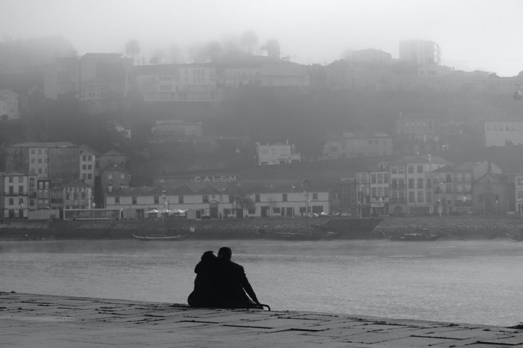 Silhouette of person sitting on rock near body of water